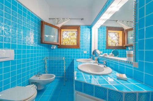 a blue tiled bathroom with two sinks and a toilet at Villa Il Varo - By Searly in Liscia di Vacca