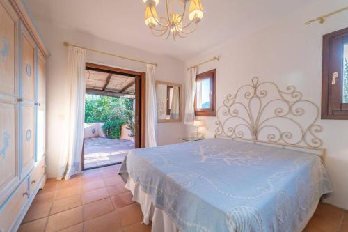 a bedroom with a blue bed and a door to a patio at Villa Il Varo - By Searly in Liscia di Vacca