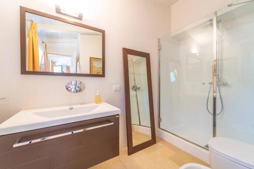 een badkamer met wastafel en douche met spiegel bij Villa Alfa - By Searly in Porto Rotondo