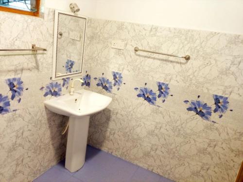 ein Badezimmer mit einem Waschbecken und blauen Blumen an der Wand in der Unterkunft Yala EAGLE NEST & Safari in Tissamaharama