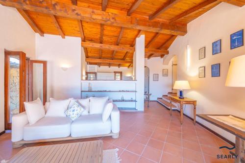 a living room with a white couch and wooden ceilings at Villa San Teodoro - By Searly in Punta Molara