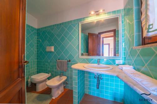 a bathroom with a sink and a toilet and a mirror at Villa San Teodoro - By Searly in Punta Molara