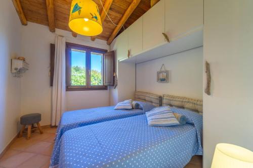 a bedroom with two beds with blue sheets and a window at Villa Molara Home - By Searly in Punta Molara