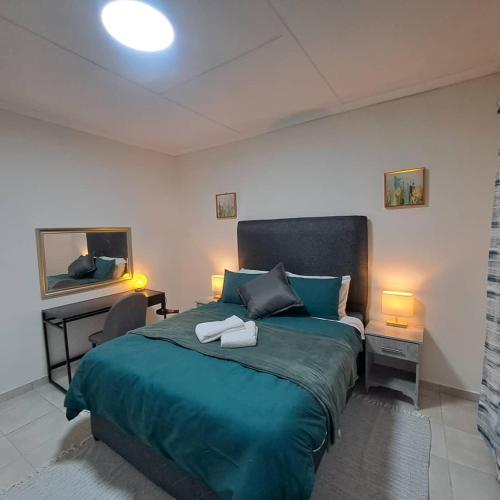 una camera da letto con un letto verde con una scrivania e uno specchio di Villa Central a Francistown