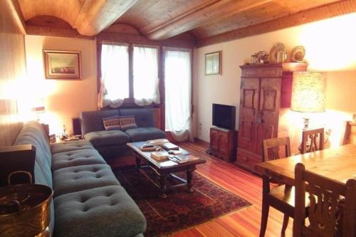 een woonkamer met een bank en een tafel bij Ca' Donatella - Mountain View Terrace & Parking in Cortina dʼAmpezzo
