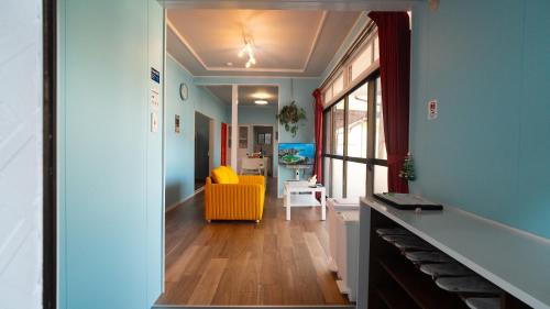 a hallway with a yellow chair and a living room at 佐世保まち宿 in Sasebo