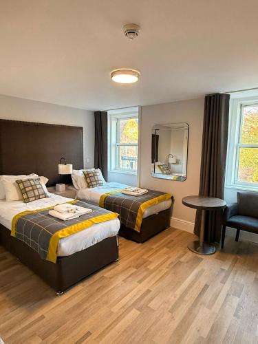 una camera da letto con due letti, un tavolo e una sedia di Dalkeith Phoenix Aparthotel Ltd a Dalkeith