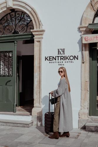 a woman standing in front of a building with a suitcase at Kentrikon 1924 Boutique Hotel, Old Town in Paphos