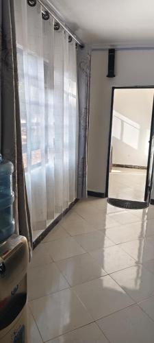 a living room with a window and a tiled floor at Mytlestayresidence in Kisii