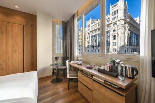 a hotel room with a bed and a desk with a coffee maker at Hyatt Centric Gran Via Madrid in Madrid