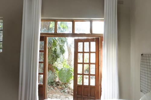 eine Tür, die zu einem Zimmer mit Fenster führt in der Unterkunft Cozy Ensuite Borrowdale in Harare