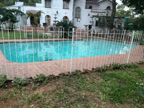 ein Zaun um einen Swimmingpool vor einem Haus in der Unterkunft Cozy Ensuite Borrowdale in Harare