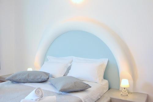a white bed with a white headboard and pillows at Ifestos Villa in Fira