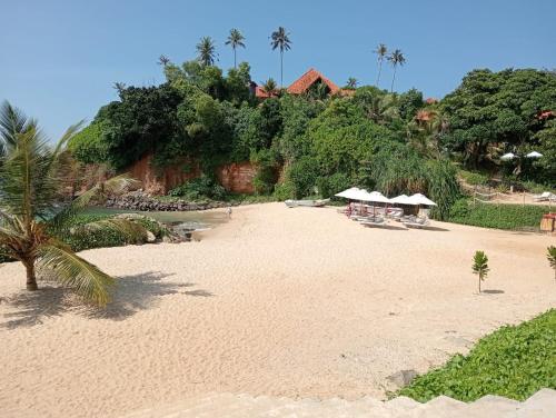 una spiaggia sabbiosa con sedie e ombrelloni di Omandi Villa a Weligama