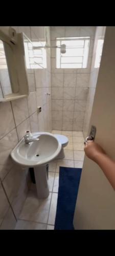 a white bathroom with a sink and a window at Fazenda Torrão da Serra in Guarulhos