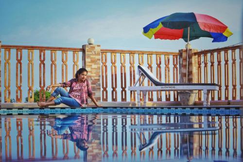 a woman sitting next to a pool with an umbrella at Aditi Ayurveda Panchkarma Retreat in Vilinjam