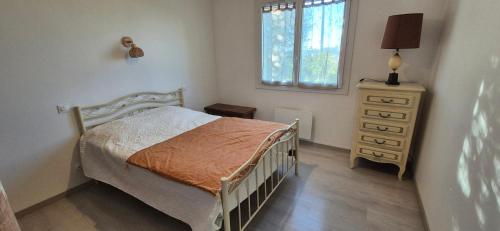 a bedroom with a bed and a dresser and a window at Maison de vacances au milieu des vignes in Cazaubon