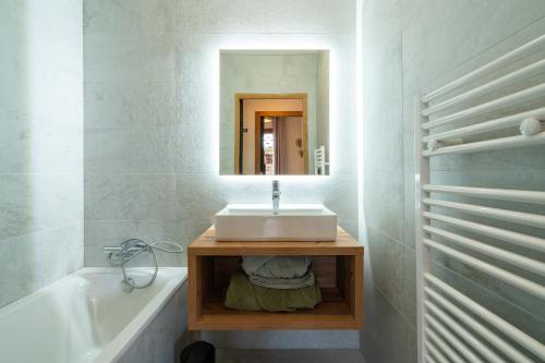 Résidence l'Alpeggio by My Mountain Resort في لي دوز آلب: حمام مع حوض وحوض استحمام ومرآة