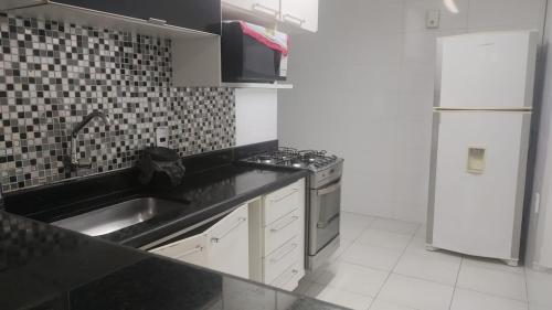 a kitchen with a sink and a stove and a refrigerator at 2 Qts próx Vila Militar, Sulacap e Campo dos Afonsos in Rio de Janeiro