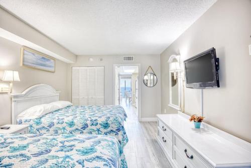 マートルビーチにあるCamelot by the Sea Resort Unit 1205 Direct Oceanfront Condo with Balconyのベッドと薄型テレビのある寝室
