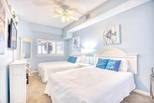 een slaapkamer met twee bedden en een plafondventilator bij Beach Cove Resort Unit 321 with Direct Oceanfront Balcony in Myrtle Beach