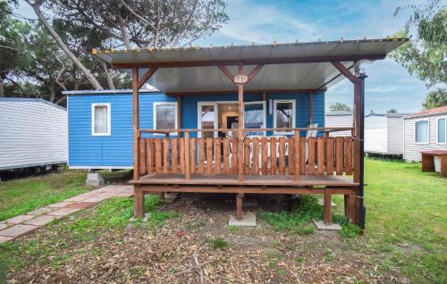 Nice Home In Tarquinia With Outdoor Swimming Pool في Porto Clementino: منزل صغير زرقاء مع شرفة خشبية كبيرة