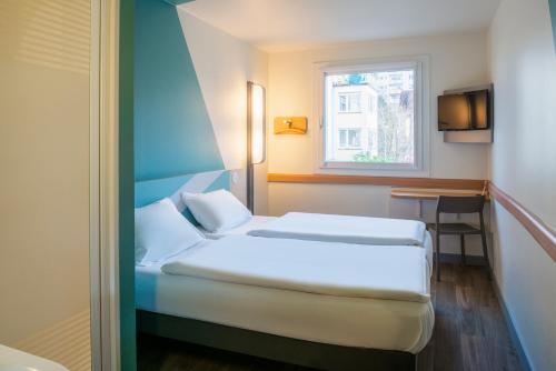 ein Hotelzimmer mit einem Bett und einem Fenster in der Unterkunft ibis budget Ulm City in Ulm