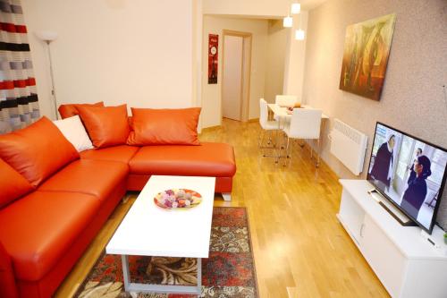 a living room with an orange couch and a table at Exclusive Skopje Apartments in Skopje