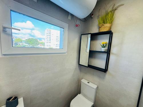 a bathroom with a white toilet and a window at Residencial Algaida in Sitio de Calahonda