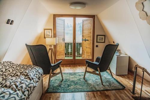 Zimmer mit 2 Stühlen, einem Bett und einem Fenster in der Unterkunft Mountain Cottage Jarilo - Scenic Fruska Gora Retreat with Fireplace, Sauna and Large Private Yard in Ležimir