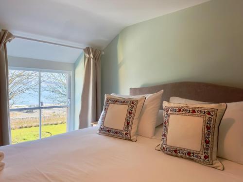 una camera da letto con un letto con due cuscini e una finestra di The Little Egret a Swansea