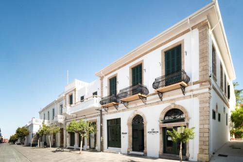 a white building with balconies on a street at Kentrikon 1924 Boutique Hotel, Old Town in Paphos
