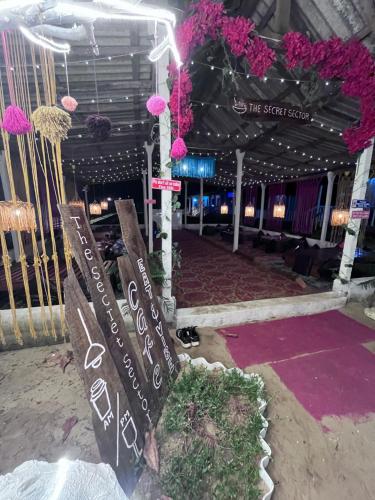 ein Schild mitten in einem Raum mit rosa Blumen in der Unterkunft The Secret Sector in Gokarna