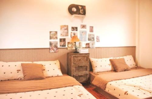 two beds in a bedroom with pictures on the wall at Chái Nho Homestay in Da Lat
