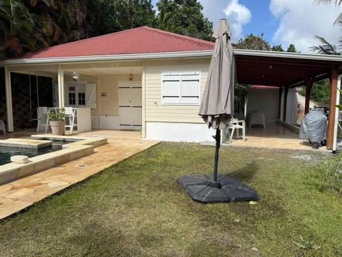 an umbrella in the grass in front of a house at Villa avec piscine privée à Rivière-Salée - 110 m² in Quartier la Fleury Guiné