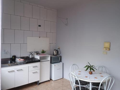 una cucina bianca con tavolo e piano cottura forno superiore di Apto confortável com Churrasqueira 03 a Cachoeira do Sul