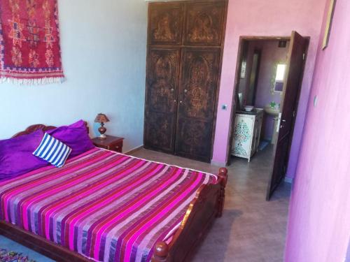 阿加迪尔Chez Maryam , pour les familles à 10 minutes de la plage的一间卧室配有一张带彩色条纹被子的床
