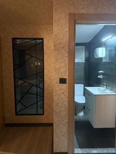 a bathroom with a mirror and a sink and a toilet at Tuzla Sahil Enjoy Hotel in Tuzla