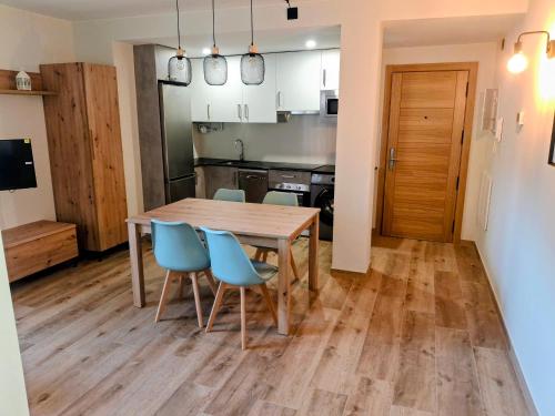 eine Küche und ein Esszimmer mit einem Holztisch und Stühlen in der Unterkunft Apartamentos Casa Domec in Castejón de Sos