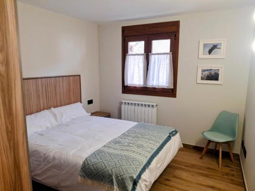 a bedroom with a bed and a window and a chair at Apartamentos Casa Domec in Castejón de Sos