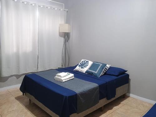 una camera da letto con un letto con lenzuola e cuscini blu di Apto confortável com Churrasqueira 03 a Cachoeira do Sul