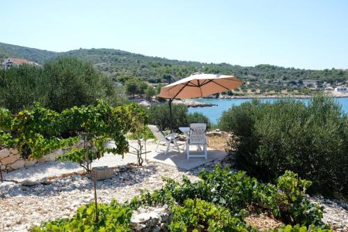 een tafel en stoelen onder een parasol naast een meer bij House Robinson house in Dolac
