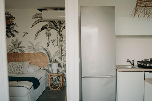 a room with a bed and a kitchen with a refrigerator at Les Villas Mandju in Sainte-Rose
