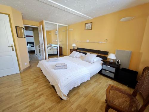 a bedroom with a large white bed and a chair at Charmante maison de village 8 personnes avec parking gratuit in Tourreilles