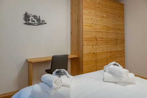 una camera con asciugamani su un letto con una sedia di Appartamenti Dolomites Elements a Caprile
