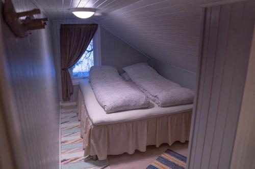 Una cama pequeña en una habitación con ventana. en Beautiful little house which offers the best of Senja, en Gibostad