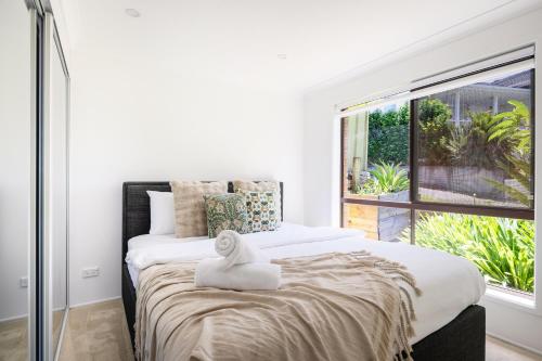 a bedroom with a large bed with a window at Oceans 21 Caves Beach in Caves Beach