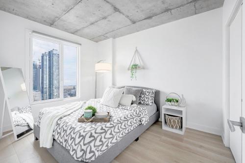 a white bedroom with a bed and a large window at Cozy Oasis Home Downtown Montreal - Free Indoor Parking-In Suite Laundry in Montréal