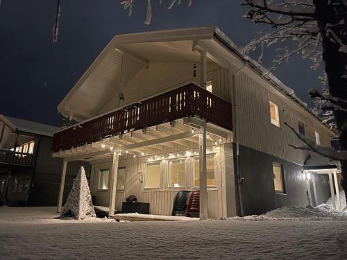 una casa con un ponte nella neve di notte di Fredelig leilighet med utsiktsplass til nordlys a Tromsø