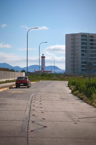 Un coche circulando por una calle con un edificio. en Rindu View Suite, en La Serena